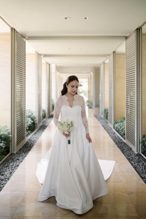 A bride with her bouquet in a sunlit corridor